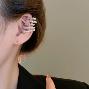 Macro detail of elegant five-layer pearl ear cuff on model ear with warm lighting