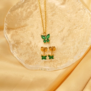 Detailansicht des goldenen Schmetterling-Schmucksets mit grünen Steinen auf Seide