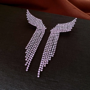 Detail of lavender drop earrings with hollow wings and long rhinestone tassels on silk