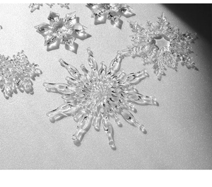 Detailed close-up of clear acrylic crystal snowflakes on a sparkling silver background