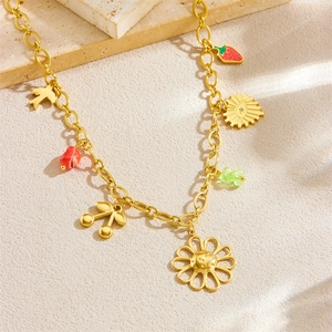 Golden chunky chain necklace with cherry, heart, and flower charms on a stone surface