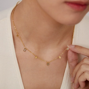 Close-up of a gold stainless steel necklace with rectangular zircons on a model