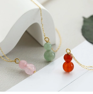 Detailed view of three natural gemstone gourd pendants in pink, green and orange carnelian