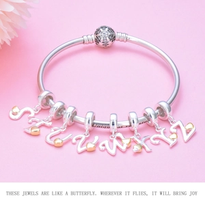 Detail view of S925 silver bracelet with cursive letter charms and gold heart accents