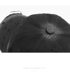 Close-up of vintage black cotton baseball cap with distressed edge and torn fabric details