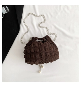 Detail view of dark brown pleated bucket bag featuring pearl-beaded silver chain straps