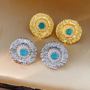 Macro detail of vintage floral stud earrings with turquoise stones on champagne silk