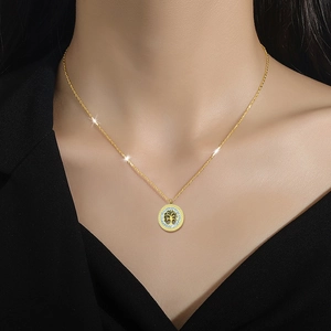 Elegant gold Tree of Life necklace with crystal halo worn on a black V-neck top