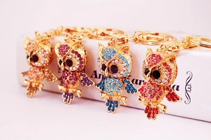 Detail of four colorful crystal owl keychains with rhinestones and golden alloy base