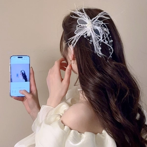 Détail d'une pince à cheveux en plumes blanches avec pampilles de perles sur un mannequin