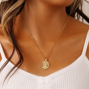 Detail of a gold coin pendant with Gemini zodiac relief on a stainless steel necklace