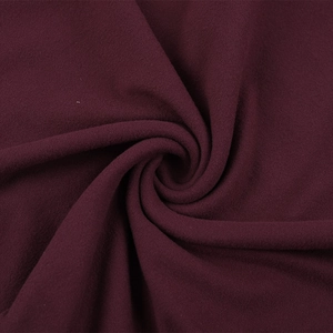 Détail de la texture douce et des couches drapées du tissu tricoté bordeaux
