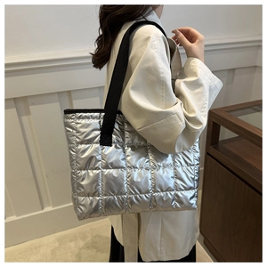 Detail of silver metallic quilted tote bag with wide black strap and grid stitching