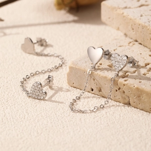 Elegant S925 silver asymmetric heart drop earrings with dangling chains on a stone
