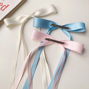 Detail showing elegant satin bow hair clips in ivory white, sky blue, and cherry pink