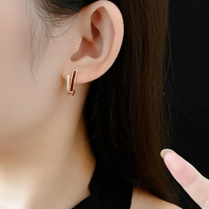 Détail d'une boucle d'oreille en or avec émail rouge et zircon sur l'oreille