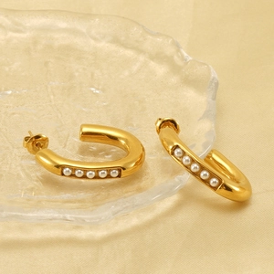 U-shaped gold titanium steel earrings with white pearls on champagne silk background