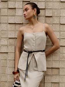 Detail of beige button-up camisole top and matching skirt with a black knotted leather belt
