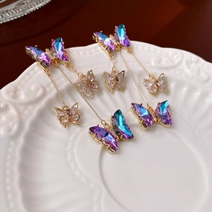 Elegant butterfly tassel earrings with purple gradient crystals on a ceramic tray