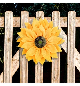 Detailed view of yellow mesh sunflower wreath hanging on a rustic wooden fence