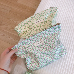 Handheld view of floral cotton makeup bags with zippers and minimalist textile labels