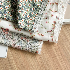 Detail of floral printed fabrics with delicate white lace edges for summer bandanas