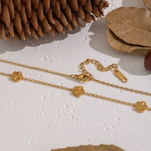 Minimalist 18K gold plated stainless steel flower necklace on white textured background