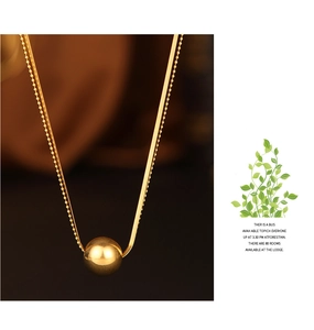 Detail of layered gold-plated snake chain necklace with round bead pendant on high-end background