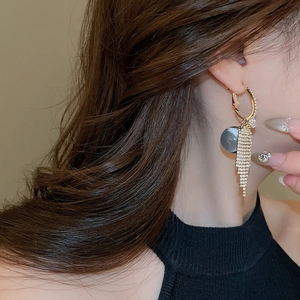 Detailed view of elegant gold tassel earrings with zircon studs and a grey resin bead