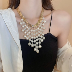 Detailed view of layered gold chain necklace with cascading V-shaped white pearls