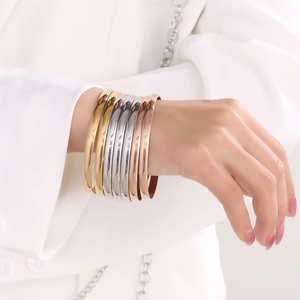 Close-up of stacked gold, silver and rose gold polished titanium steel bracelets on wrist