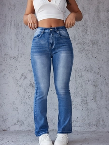 Detail shot of high waisted distressed blue jeans showing wash texture and seam quality