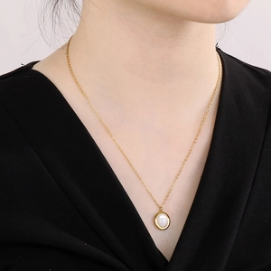 Close-up of elegant gold chain necklace with oval cat eye stone pendant on model