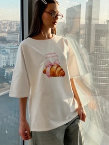 Λεπτομέρεια λευκού βαμβακερού T-shirt με σχέδιο κρουασάν, ροζ φιόγκο και ρωσικό κείμενο