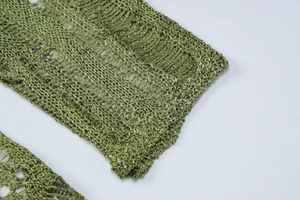 Detailed close-up of green crochet knit fabric featuring intricate openwork mesh patterns