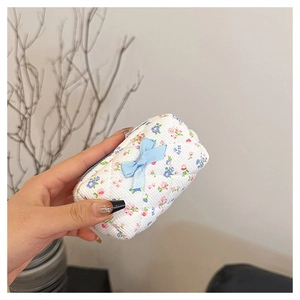 Close-up of a quilted floral mini pouch with a blue bow held in hand for scale