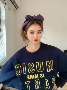Close-up of a wide purple satin bow headband paired with a navy blue sweatshirt