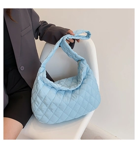 Close-up of light blue quilted tote bag with soft padded texture and top handle detail
