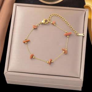 Gold stainless steel bracelet with orange gravel stones on a jewelry display box