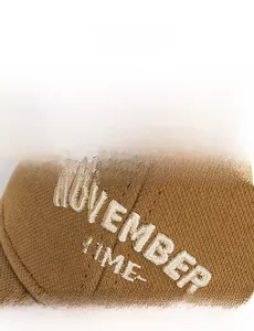 Detail of November embroidery on brown cotton twill baseball cap with vintage texture