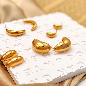 Detailed macro view of 18K gold teardrop earrings in various sizes on a white stand