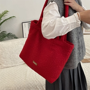 Detailed view of red plush tote bag styled with a white shirt and grey vest for daily use