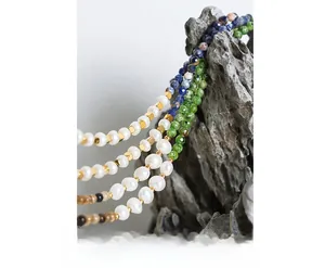 Detail of natural freshwater pearls and colorful gemstones necklace on gray rock