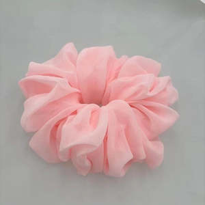 Close-up of a soft pink chiffon scrunchie showing the pleated texture and fabric detail