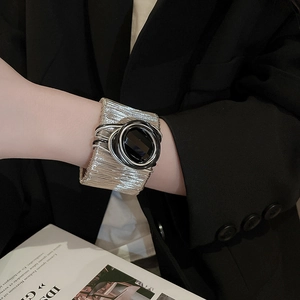 Macro detail of silver wire-wrapped cuff bracelet featuring a large black oval gemstone