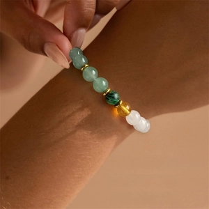 Nahaufnahme eines bunten 8mm Naturstein-Armbandes mit Goldakzenten an einem Handgelenk