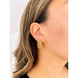 Macro shot of gold-plated twisted C-shaped earrings with rhinestones on model's ear