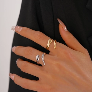 Close-up of minimalist gold and silver snake-style open rings on model's hand