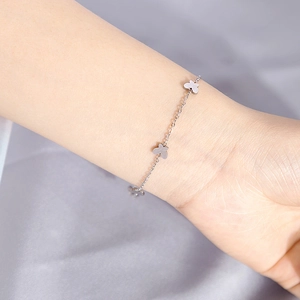 Close-up of minimalist silver butterfly bracelet on wrist with elegant silk background