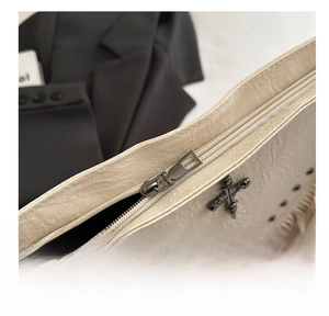 Close-up of smooth metal zipper and pebbled leather texture on vintage tassel bag